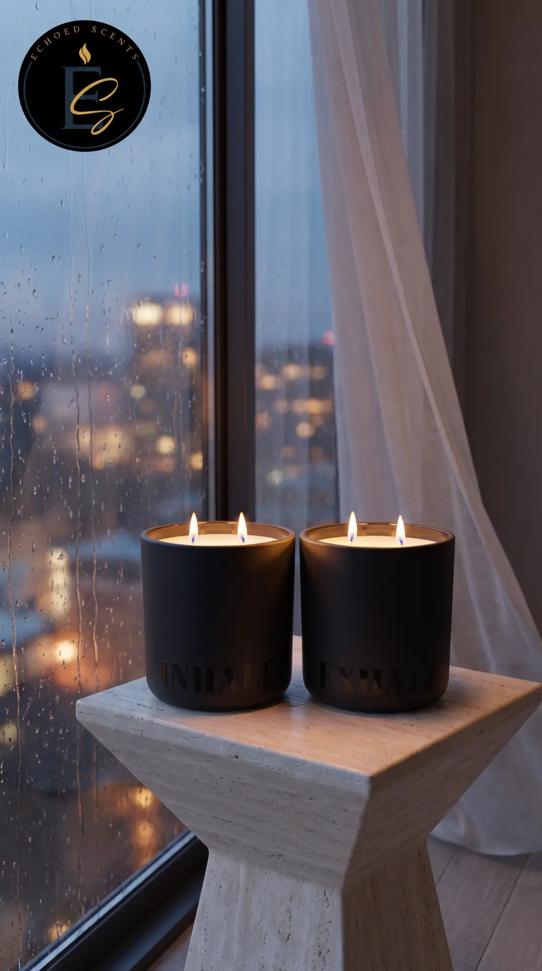 The lit Inhale and Exhale black candles beside a rainy window, city lights glowing softly behind the glass.
